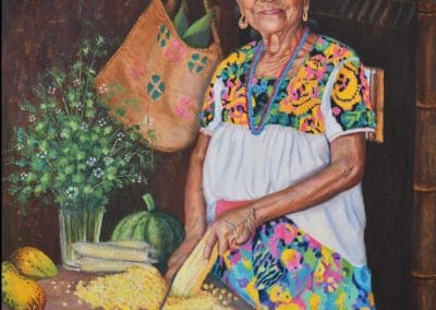 Foto de mujer Nahua, madura, sonriendo, con un vestido floreado. La mujer esta cocinando