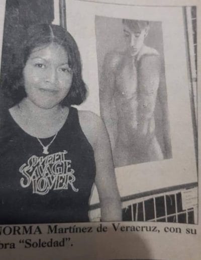 Picture in black and white of a newspaper publication of Norma Martinez, Nahua Artist posing in front of her Nahua Art
